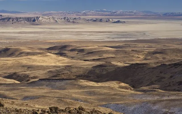 View over brown hills to the pale Black Rock Desert playa and distant mountains in Nevada
